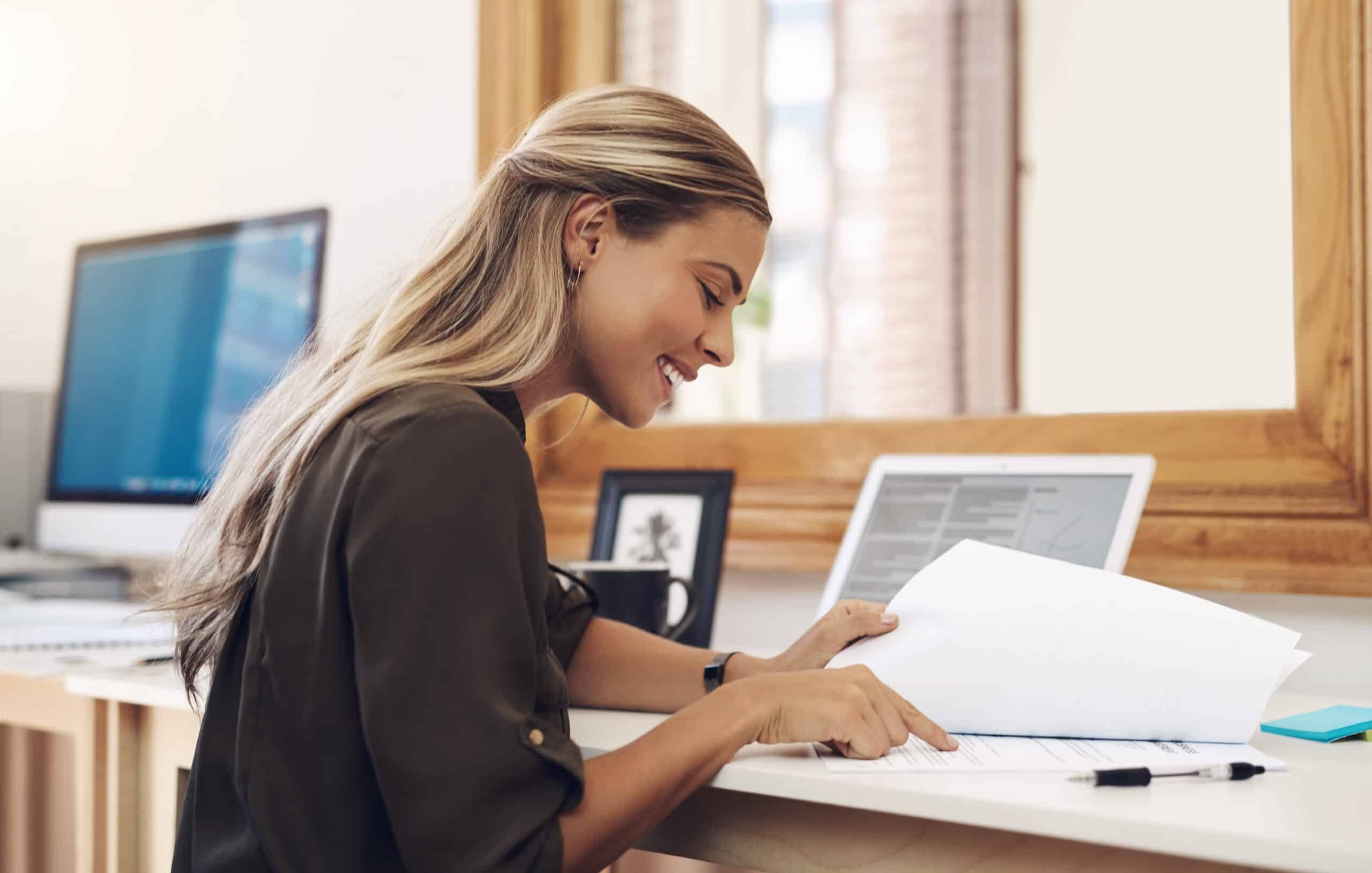 Paperwork, business woman and accountant reading report for information, financial data or analysis. Documents, auditor and happy female professional check contract, review and bookkeeping in office. AdobeStock 610559918 scaled Utilities