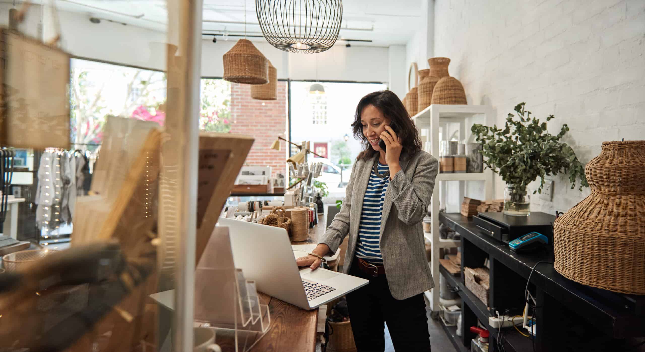 Smiling Asian woman talking on a cellphone in her store SAP Solutions for Retail, customer products